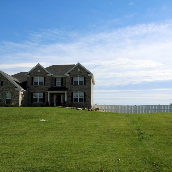 Two-story home surrounded by white vinyl fencing