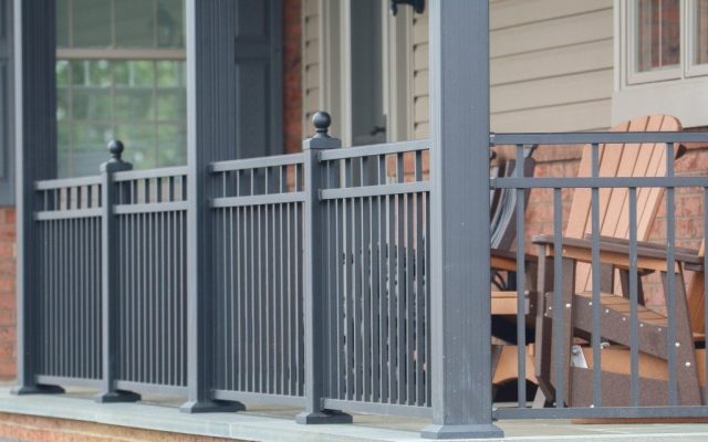 Gray aluminum porch railing around wooden furniture