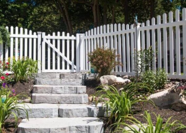 stone steps with shrubs leading up to white picket fence with gate